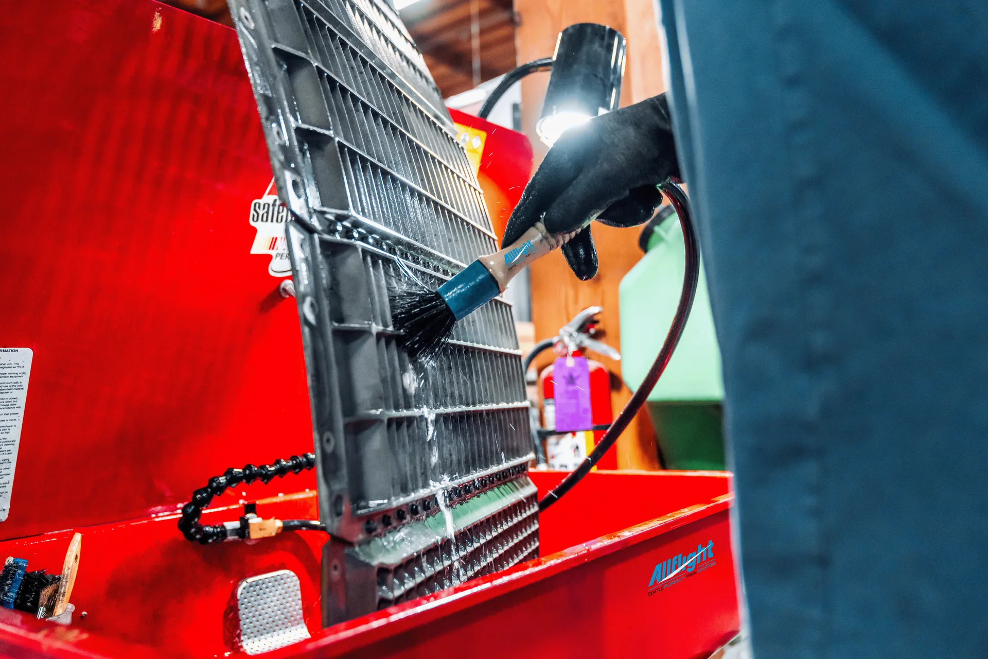 Gloved technician cleaning a metal component at an Allflight work station